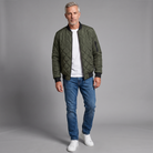 Men's diamond-quilted bomber jacket in dark green, full-body standing shot