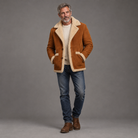Men's suede shearling-lined jacket, full-body standing shot, gray studio background