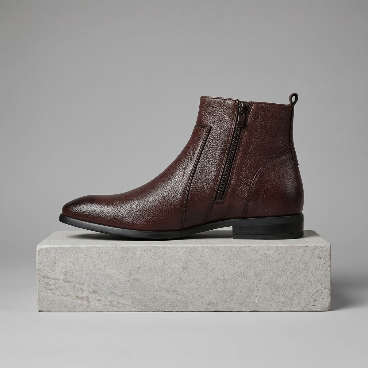 Men's pointed-toe side-zip leather boots in dark brown, straight-on gray pedestal shot